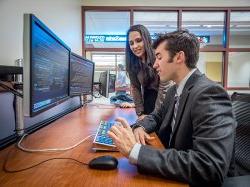 Students from the Feliciano School of Business analyzing stocks on double monitors.